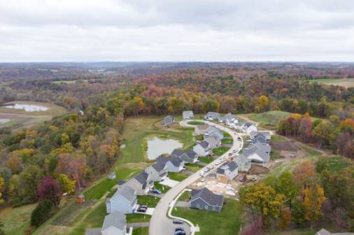 Aerial shot of a suburban area during fall, highlighting the rich colors of autumn leaves and the layout of homes.